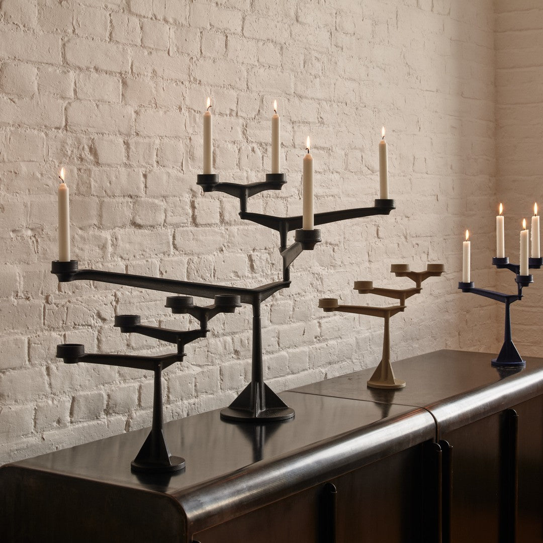 "Elegant black, bronze, and navy candle holders with a modern tree branch design, displayed on a sleek surface."