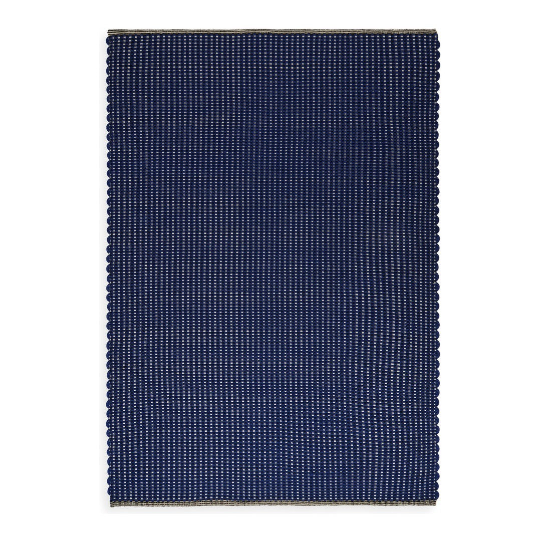 Navy blue rectangular rug with a subtle striped pattern and scalloped edges, adding texture and style.