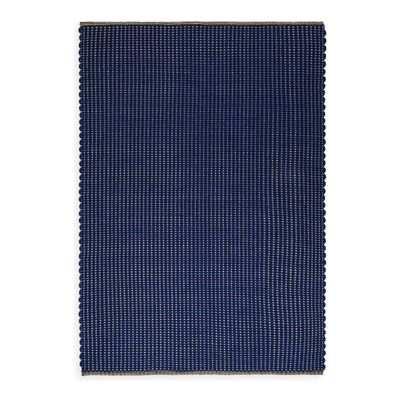 Navy blue rectangular rug with a subtle striped pattern and scalloped edges, adding texture and style.