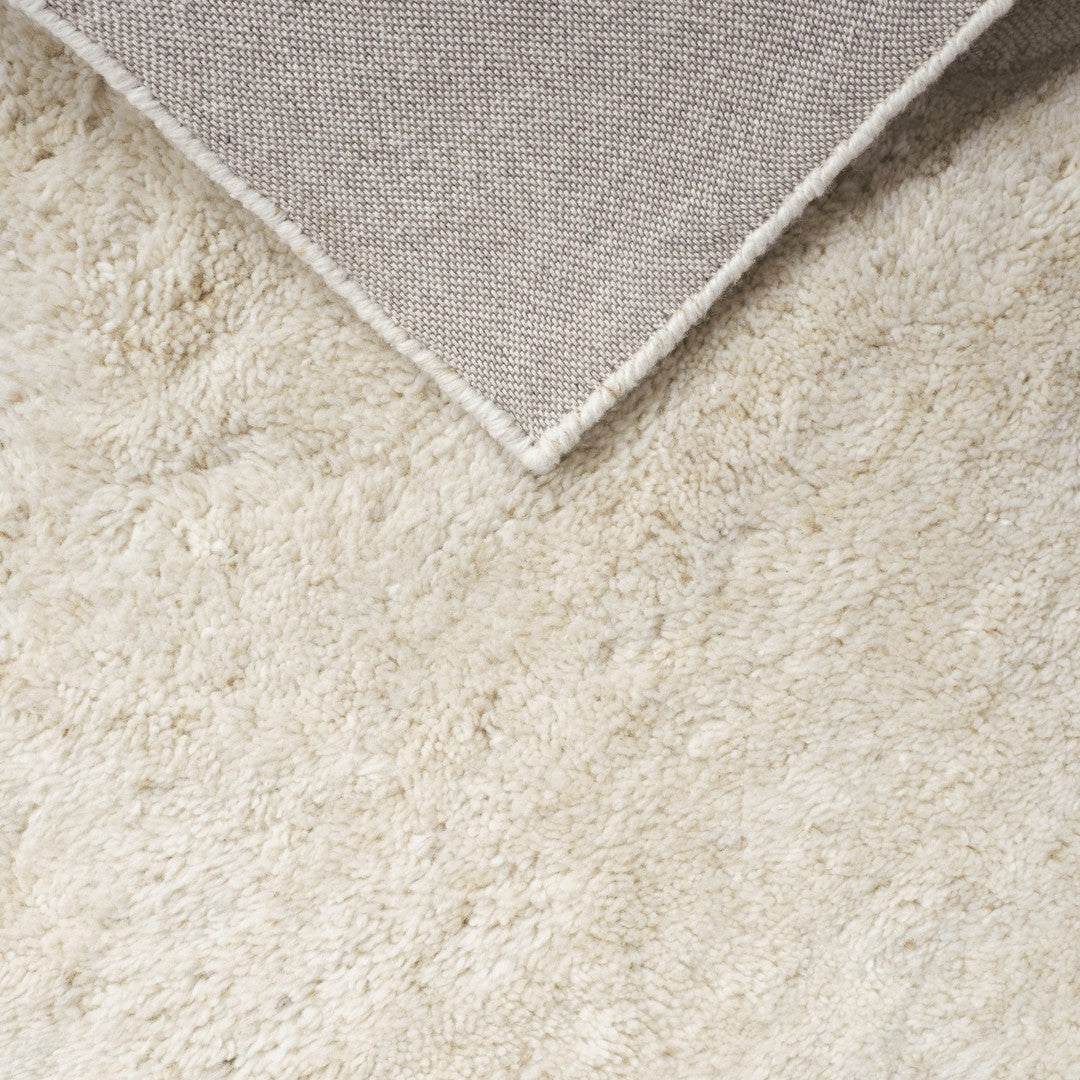 Creamy white textured rug with a soft, plush surface and a contrasting gray corner. Perfect for cozy spaces.