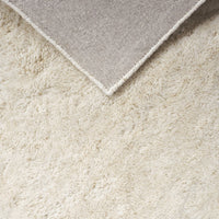 Creamy white textured rug with a soft, plush surface and a contrasting gray corner. Perfect for cozy spaces.