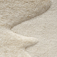 Beige textured rug featuring soft, wavy patterns and a plush finish for a cozy interior accent.