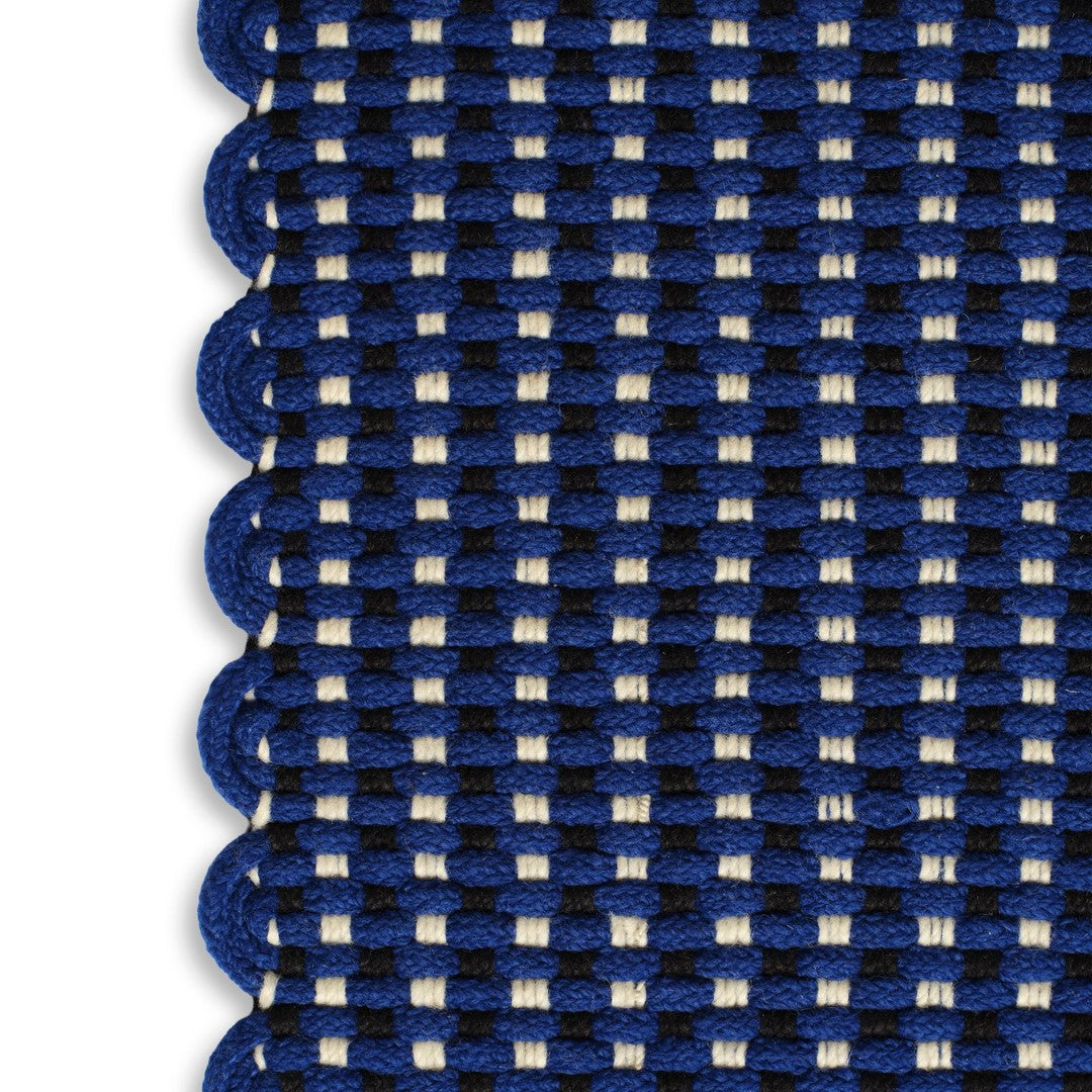 Navy blue and cream patterned rug with scalloped edges, featuring a woven check design.