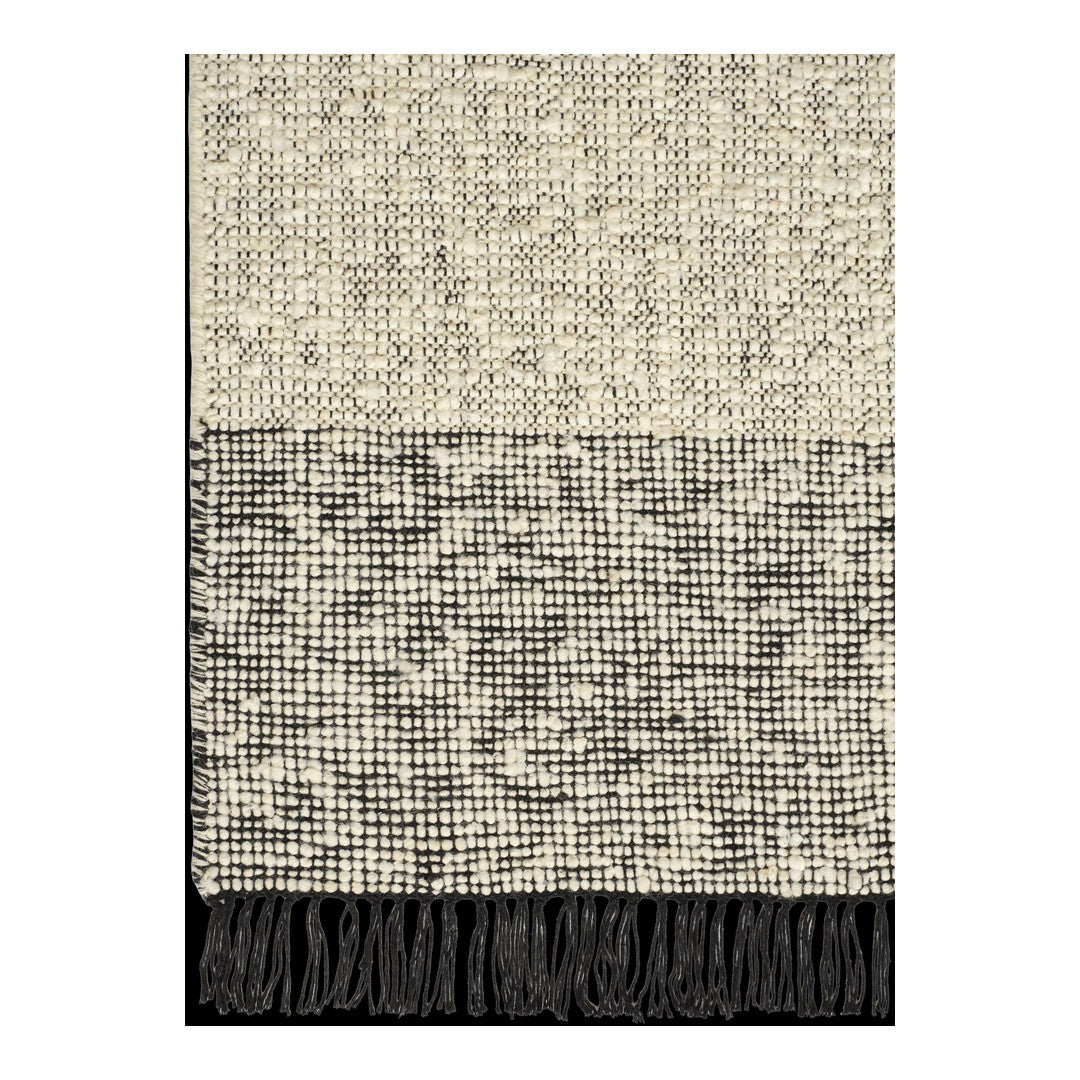 Textured throw blanket featuring a cream and black pattern with fringed edges. Modern and cozy decor accent.