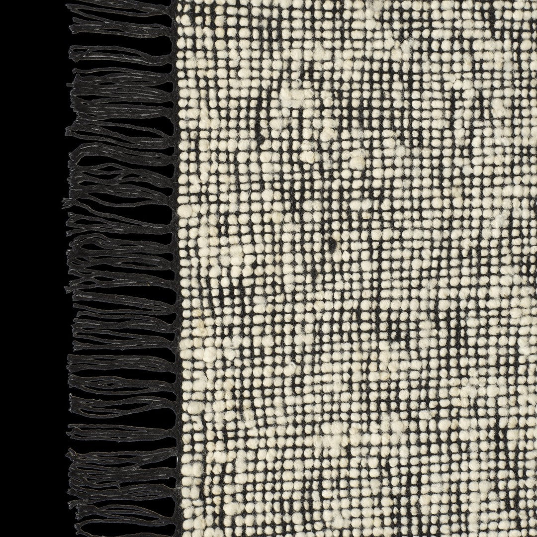 Black and cream textured rug with a woven pattern and fringed edges. Ideal for modern home decor.