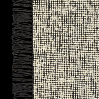 Black and cream textured rug with a woven pattern and fringed edges. Ideal for modern home decor.