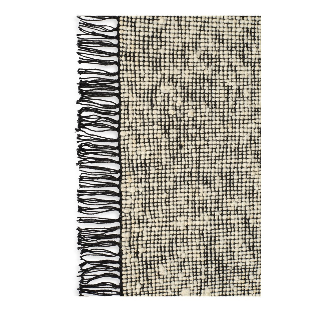 Textured beige and cream blanket with a black fringed edge and subtle checkered pattern. Perfect for cozy decor.