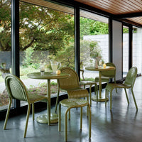 Green café furniture set against large windows, featuring sleek lines and a textured pattern. Ideal for modern spaces.