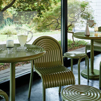 Green striped outdoor table and chairs with a modern aesthetic, surrounded by a nature-inspired setting.