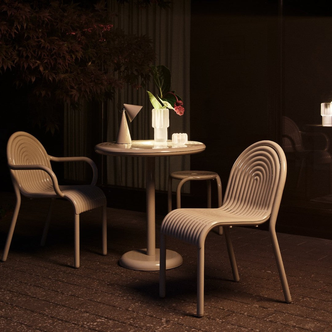 Beige ribbed chairs and round table set against a dark backdrop, featuring sleek lines and soft textures.