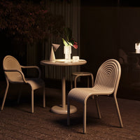 Beige ribbed chairs and round table set against a dark backdrop, featuring sleek lines and soft textures.