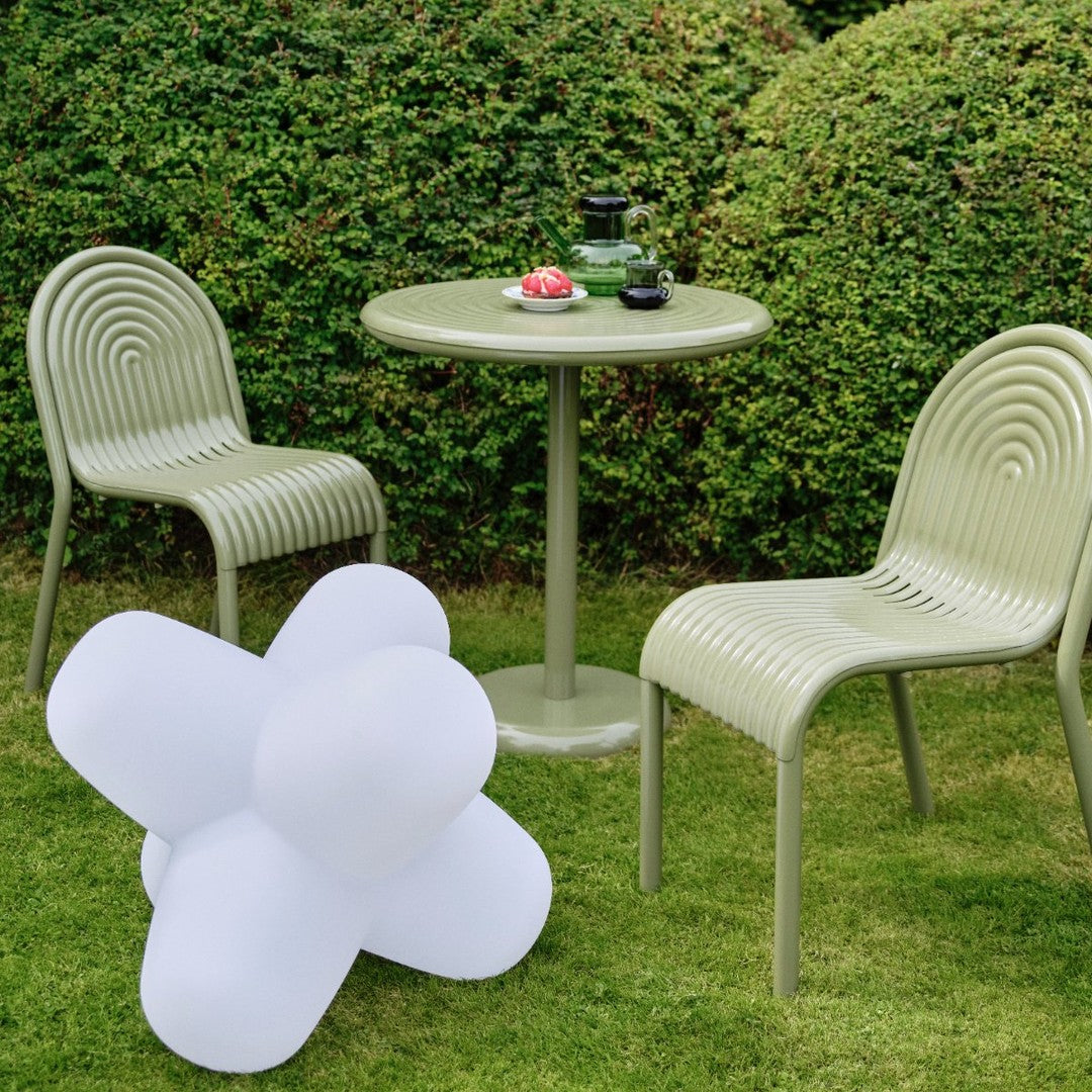 Modern outdoor set featuring olive green chairs and table, with a white star-shaped decor piece on lush grass.