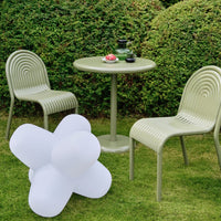 Modern outdoor set featuring olive green chairs and table, with a white star-shaped decor piece on lush grass.