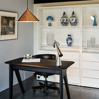 Sleek black desk with a wooden geometric pendant light, surrounded by blue and white decorative vases. Modern decor.