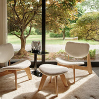 Soft white upholstery and light wood accents blend seamlessly with natural greenery through large windows.