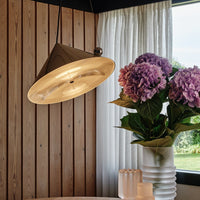 Sleek gold pendant light with a matte brown cone, paired with vibrant purple hydrangeas and soft white curtains.