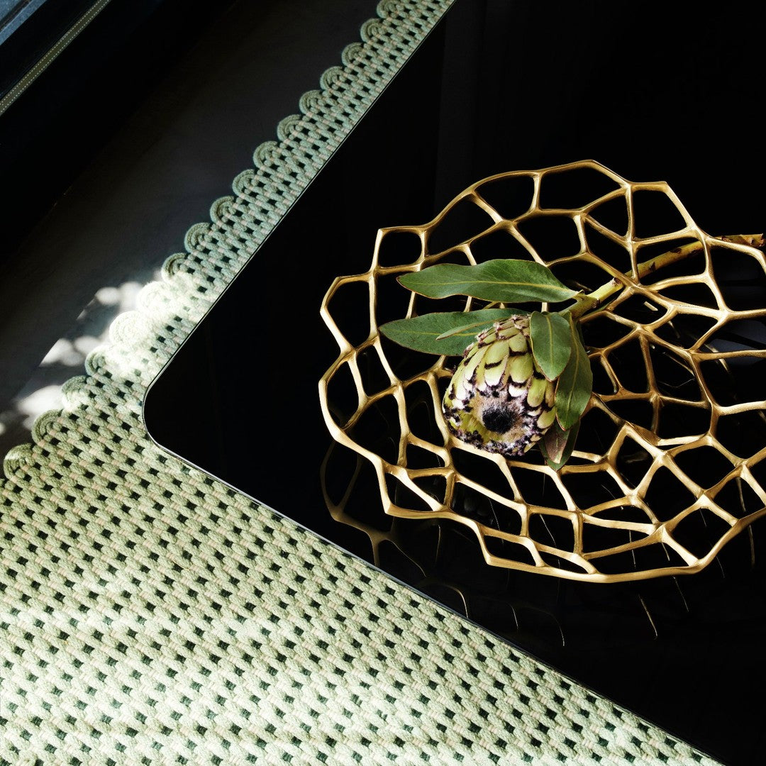 Decorative black plate with gold geometric pattern, highlighted by a green and white scalloped placemat.