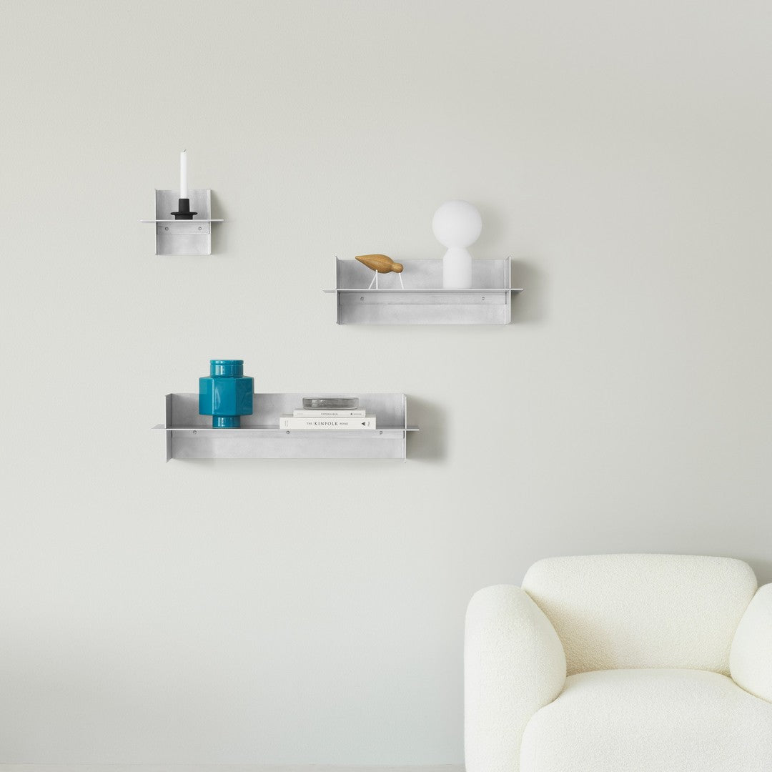 Modern metal wall shelves in silver, featuring blue and white decor accents against a soft gray background.