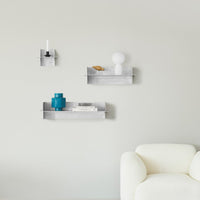 Modern metal wall shelves in silver, featuring blue and white decor accents against a soft gray background.