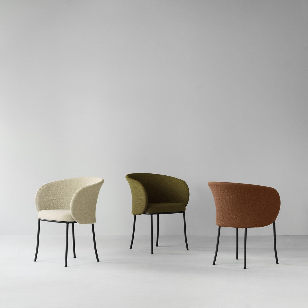 Three stylish chairs in cream, olive green, and terracotta, featuring textured upholstery and sleek black legs.
