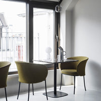 Olive green chairs, sleek black table, and a monochrome decor create a modern, minimalist dining space.