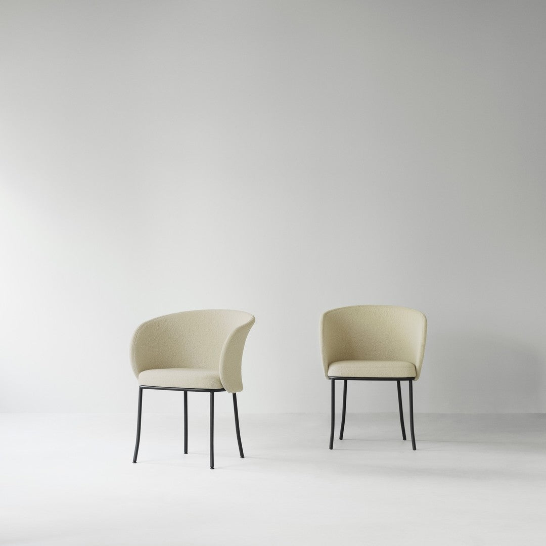 Minimalist cream chairs with soft upholstery and sleek black metal legs, set against a light gray background.