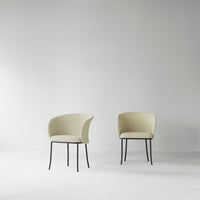 Minimalist cream chairs with soft upholstery and sleek black metal legs, set against a light gray background.