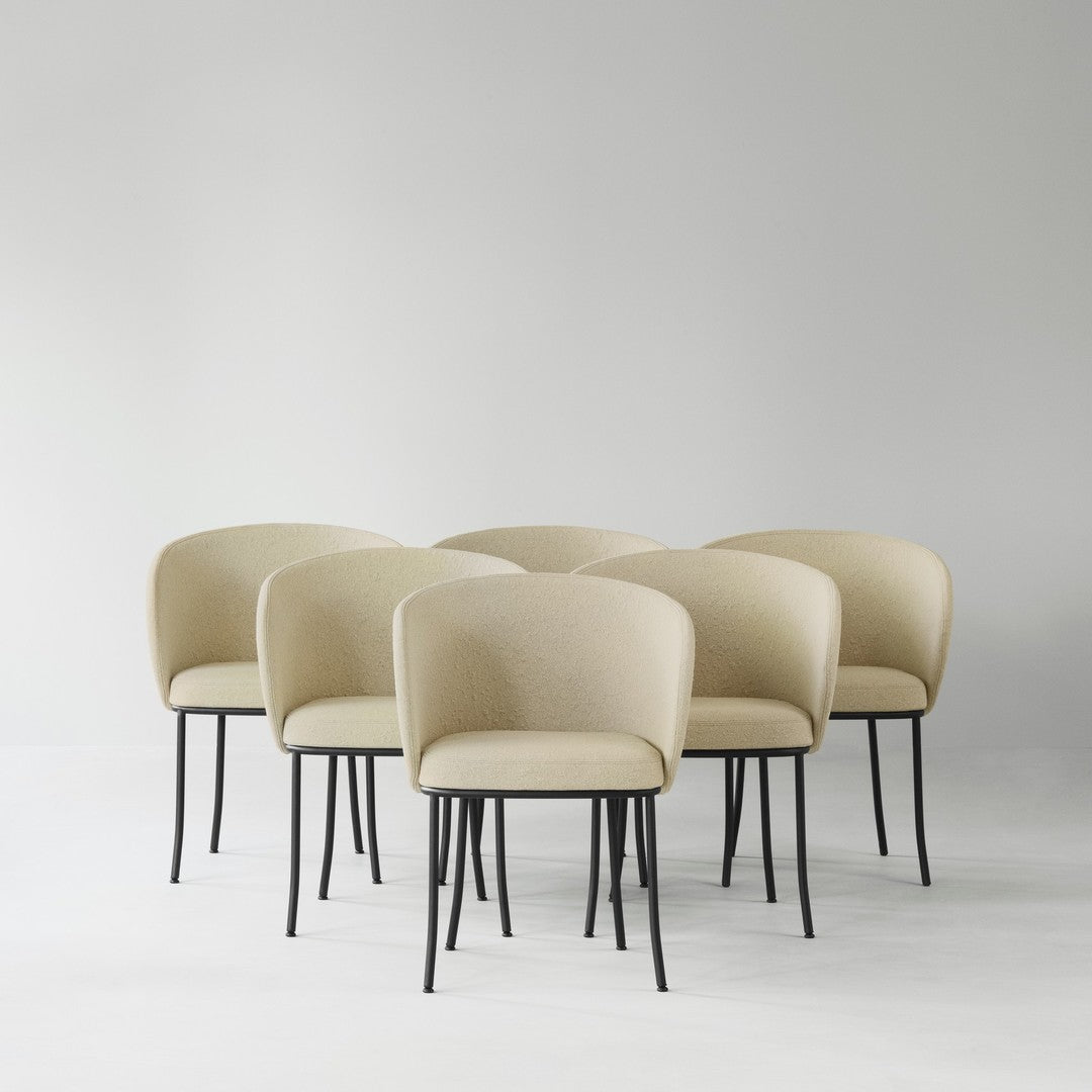 Beige fabric dining chairs with smooth texture and sleek black metal legs, arranged in a minimalist setting.