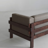 Brown fabric sofa with a dark wood frame, featuring a sleek, modern design and minimalistic patterns.