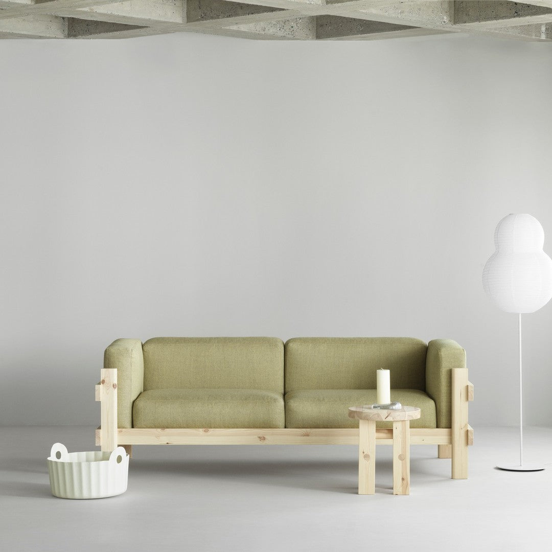 Olive green sofa with natural wood frame, paired with a white accent lamp and light gray surroundings.