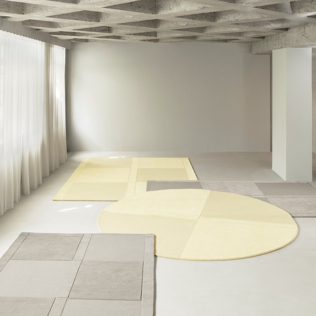 Modern area rugs in soft yellow and gray tones with geometric patterns on a minimalist floor. Elegant and stylish decor.