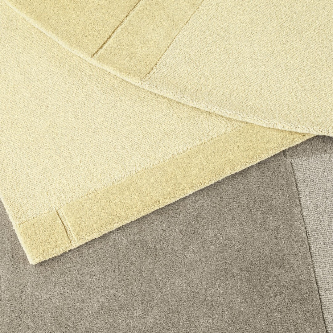 Textured rugs in soft yellow and muted gray colors, featuring a blend of smooth and plush patterns.