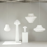 White textured pendant and floor lamps with modern shapes in a minimalist setting. Elegant, soft color palette.