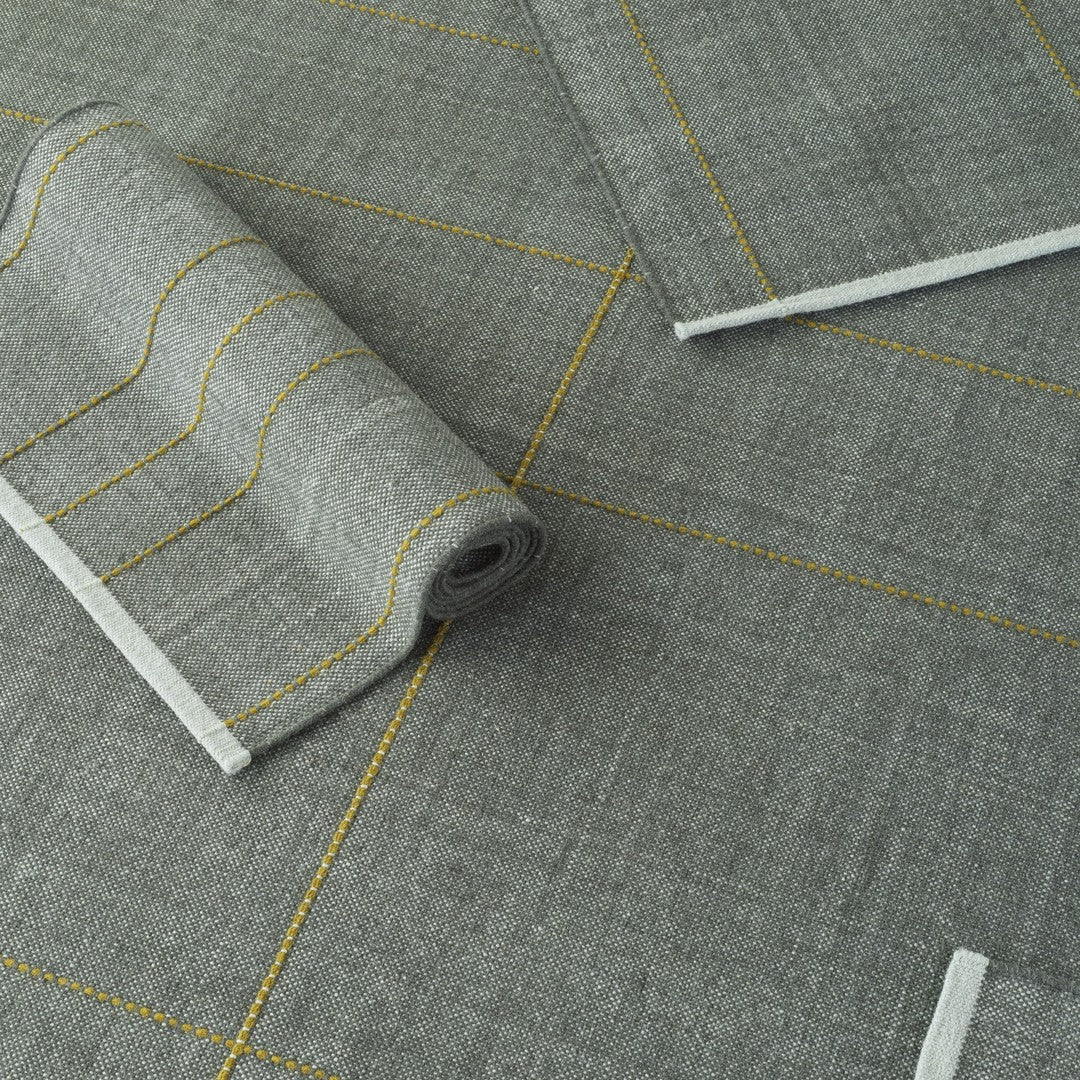 Gray fabric with yellow geometric patterns and stripes, featuring subtle textures and a modern design.