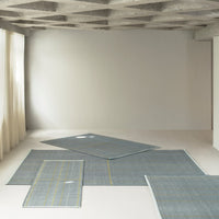 Blue area rugs with subtle plaid patterns and contrasting yellow lines on a minimalist background.