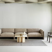Beige sofa with textured stripes, light gray walls, and a neutral rug featuring subtle patterns. Elegant minimalist design.