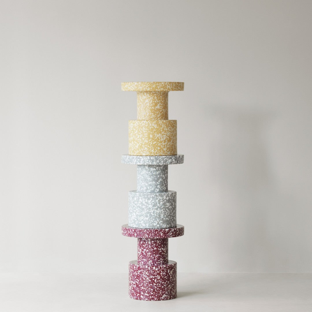 Colorful stacked decor in yellow, light blue, and burgundy with speckled patterns against a neutral background.