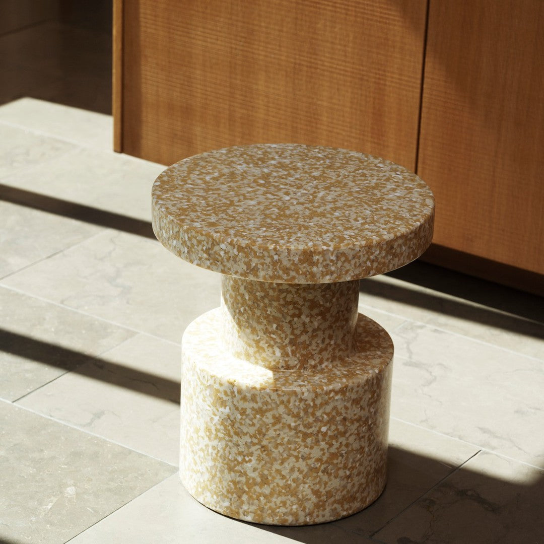 Round stool featuring a speckled yellow and white pattern with a modern cylindrical design. Ideal for stylish decor.