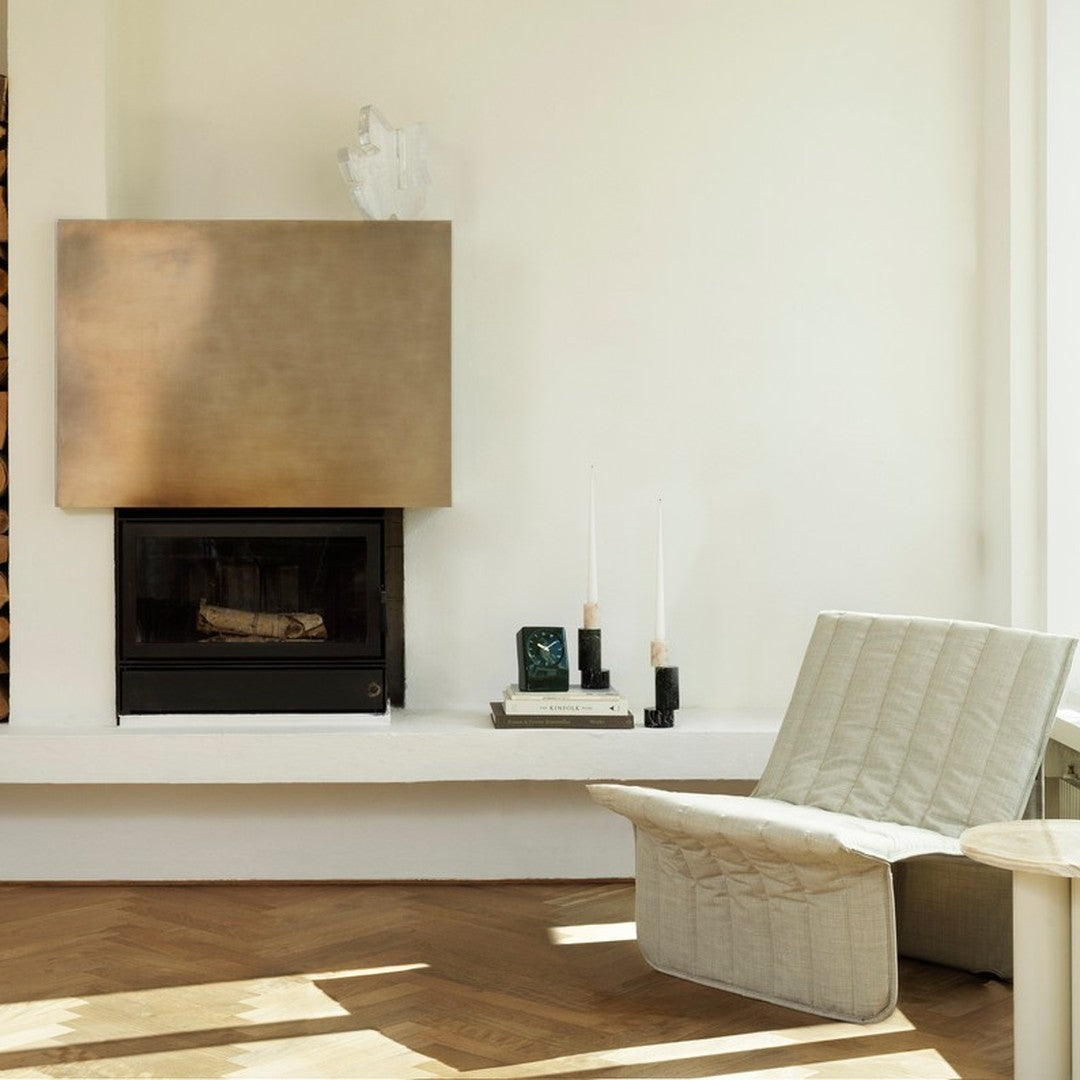 Modern living room featuring a minimalist gold fireplace, beige furniture, and warm wood flooring for a cozy ambiance.