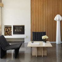 Two sleek black upholstered chairs with a quilted pattern, paired with a minimalist light wood coffee table.