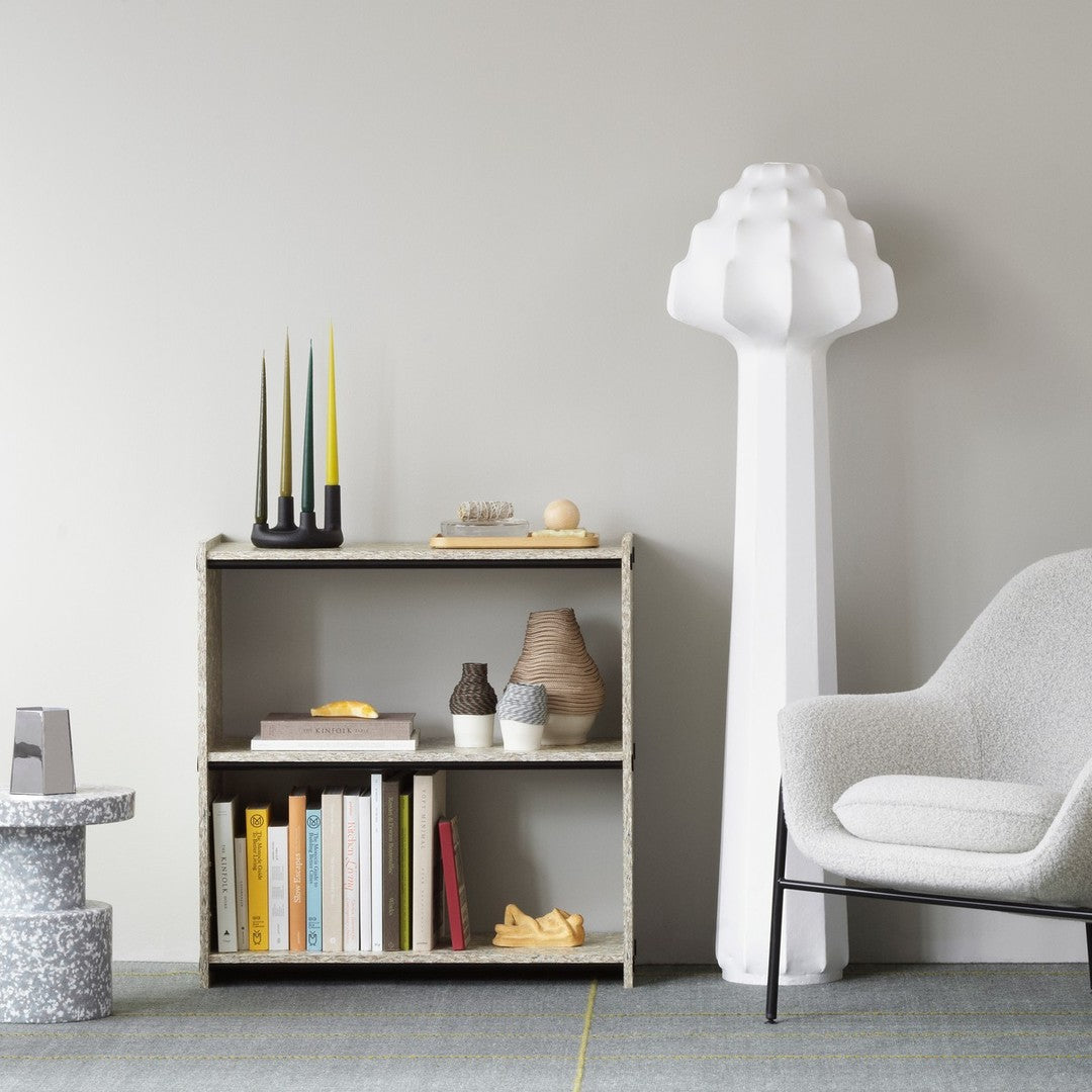Modern bookshelf in neutral tones with white, yellow, and gray accents, featuring geometric shapes and minimalist decor.