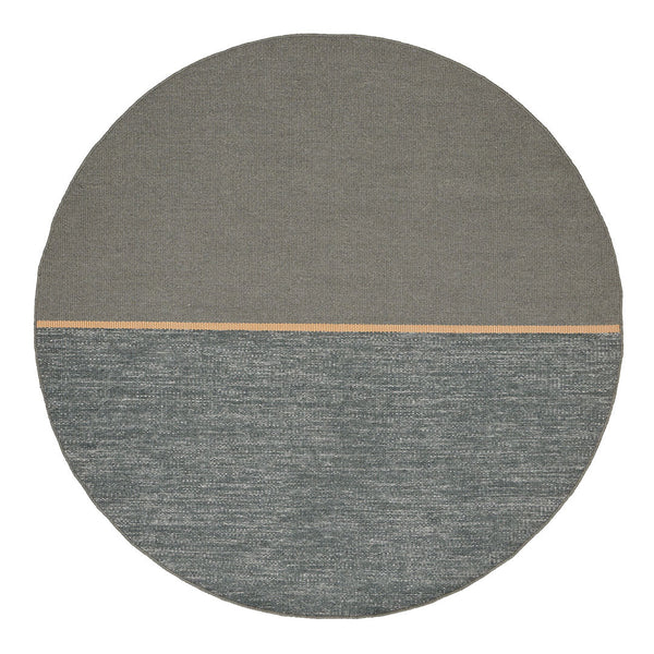 Round rug featuring a smooth gray top half and textured teal bottom half with a subtle wooden accent line.