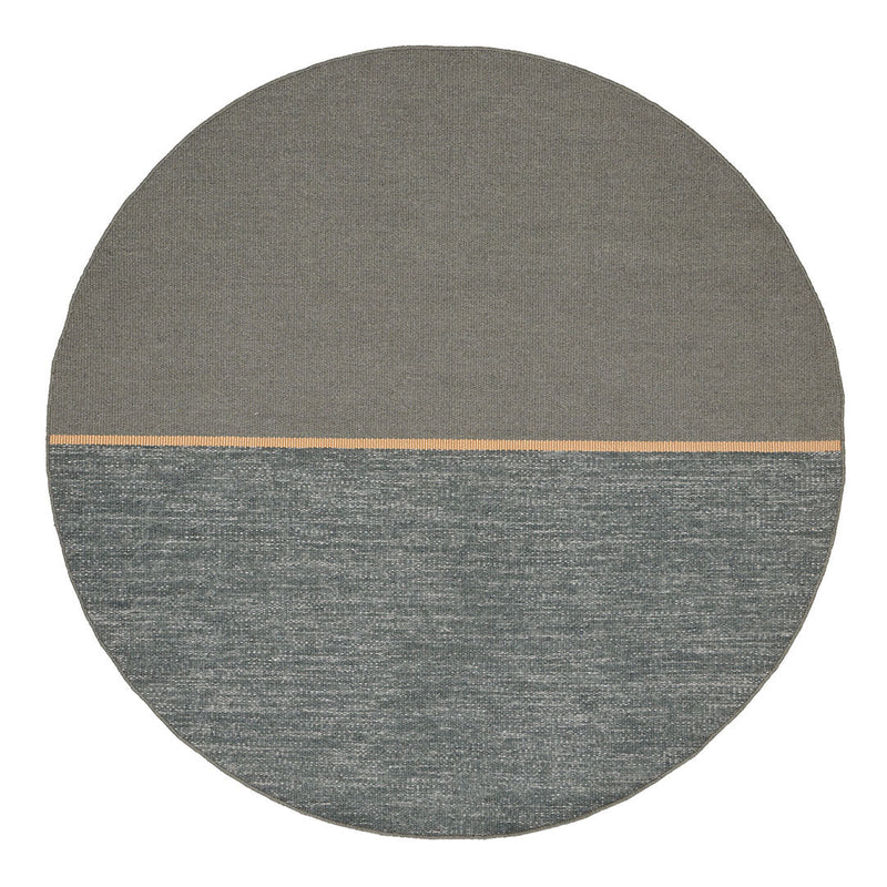 Round rug featuring a smooth gray top half and textured teal bottom half with a subtle wooden accent line.