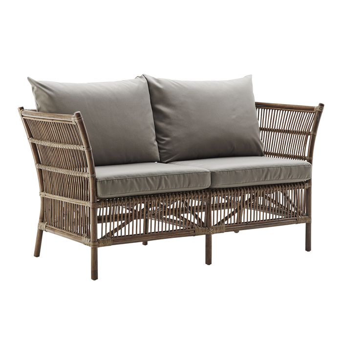 Gray cushion loveseat with a natural woven rattan frame and an intricate crisscross pattern, perfect for outdoor decor.