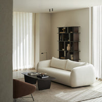 Modern white curved sofa in a neutral-toned living room with soft textures and subtle, earthy color accents.