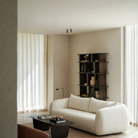 Cozy cream sofa with textured upholstery, minimalist dark wood bookshelf, and soft neutral tones in a serene living space.