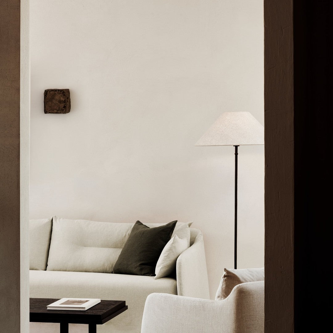 Elegant beige sofa with dark green accent pillow, complemented by neutral walls and black wooden table.