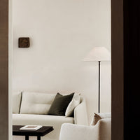 Elegant beige sofa with dark green accent pillow, complemented by neutral walls and black wooden table.