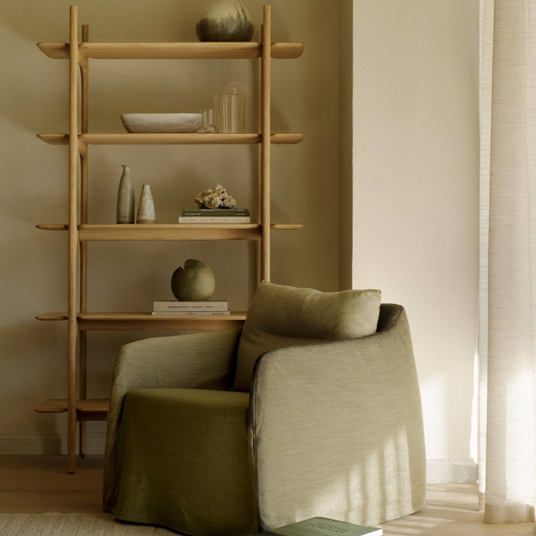 Wooden shelving unit with neutral tones, featuring soft green and beige patterns on the cozy armchair.