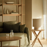 Cozy green pillows and sofa with natural wood accents; warm neutral tones enhance the inviting atmosphere.
